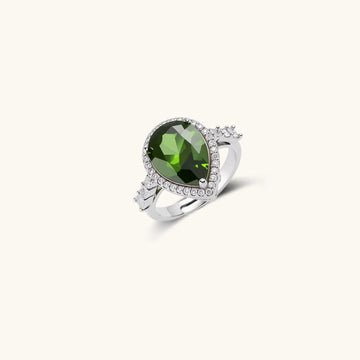 White gold plated jewelry set with green teardrop gemstones and cubic zirconia halos on cream background.