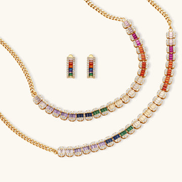 Gold-plated jewelry set featuring rainbow baguette-cut cubic zirconia stones in geometric design on cream background